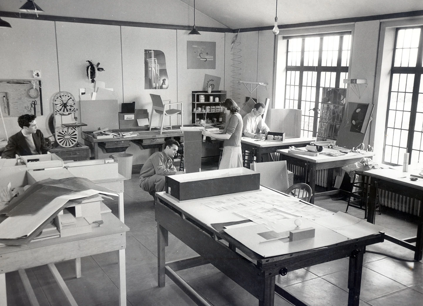 Cranbrook. Charles Eames is crouched on floor and behind him is a prototype chair for Kleinhans