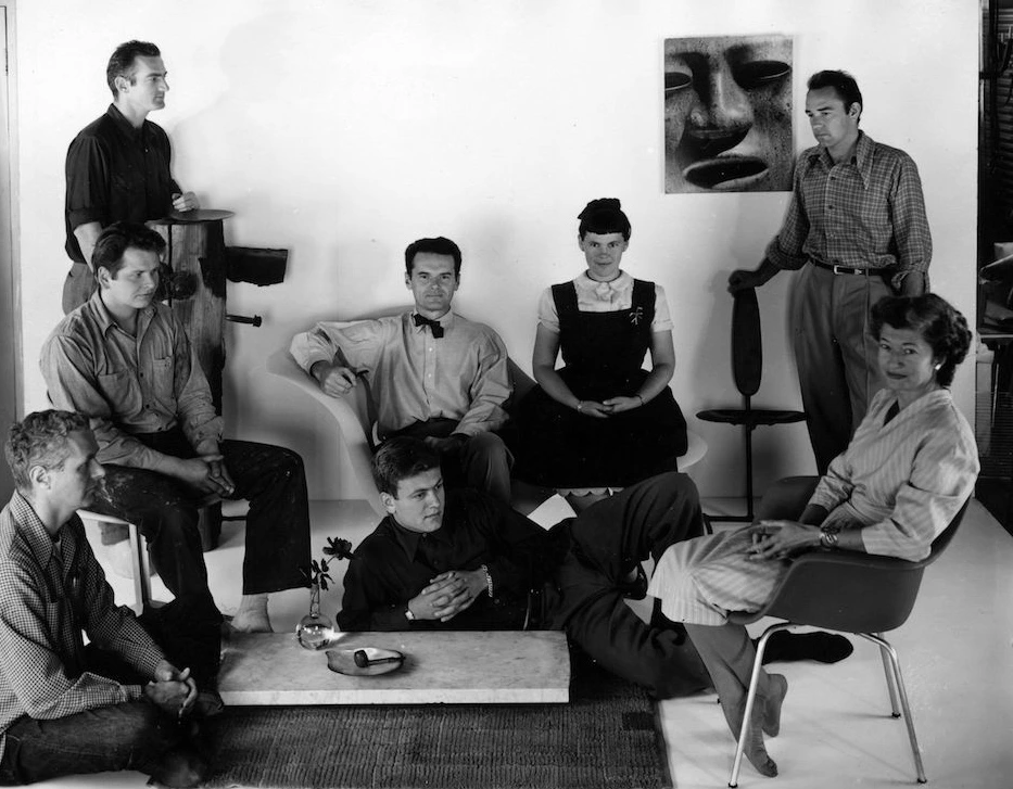 Charles and Ray Eames sitting on their LaChaise with various staff members