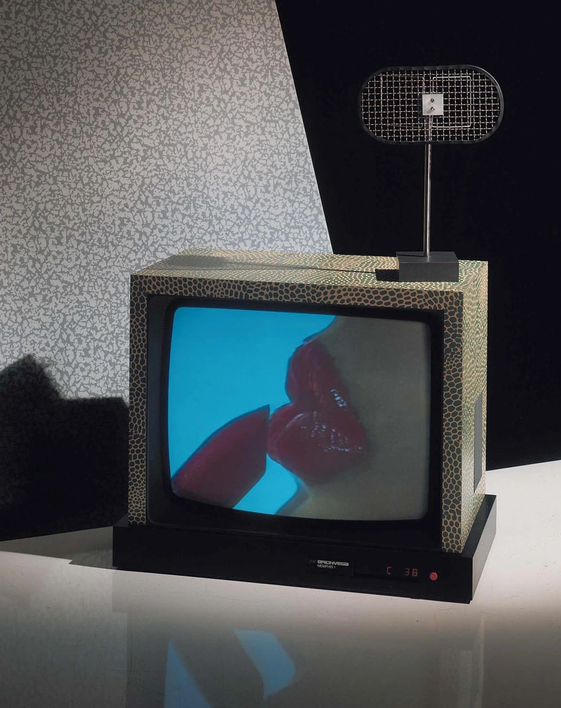 Brionvega television set broadcasting an image of a lipstick and red lips on a blue background