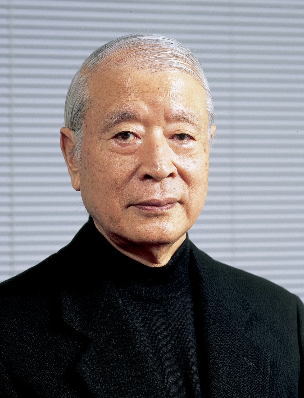 Kazumasa Nagai wearing black, looking into camera