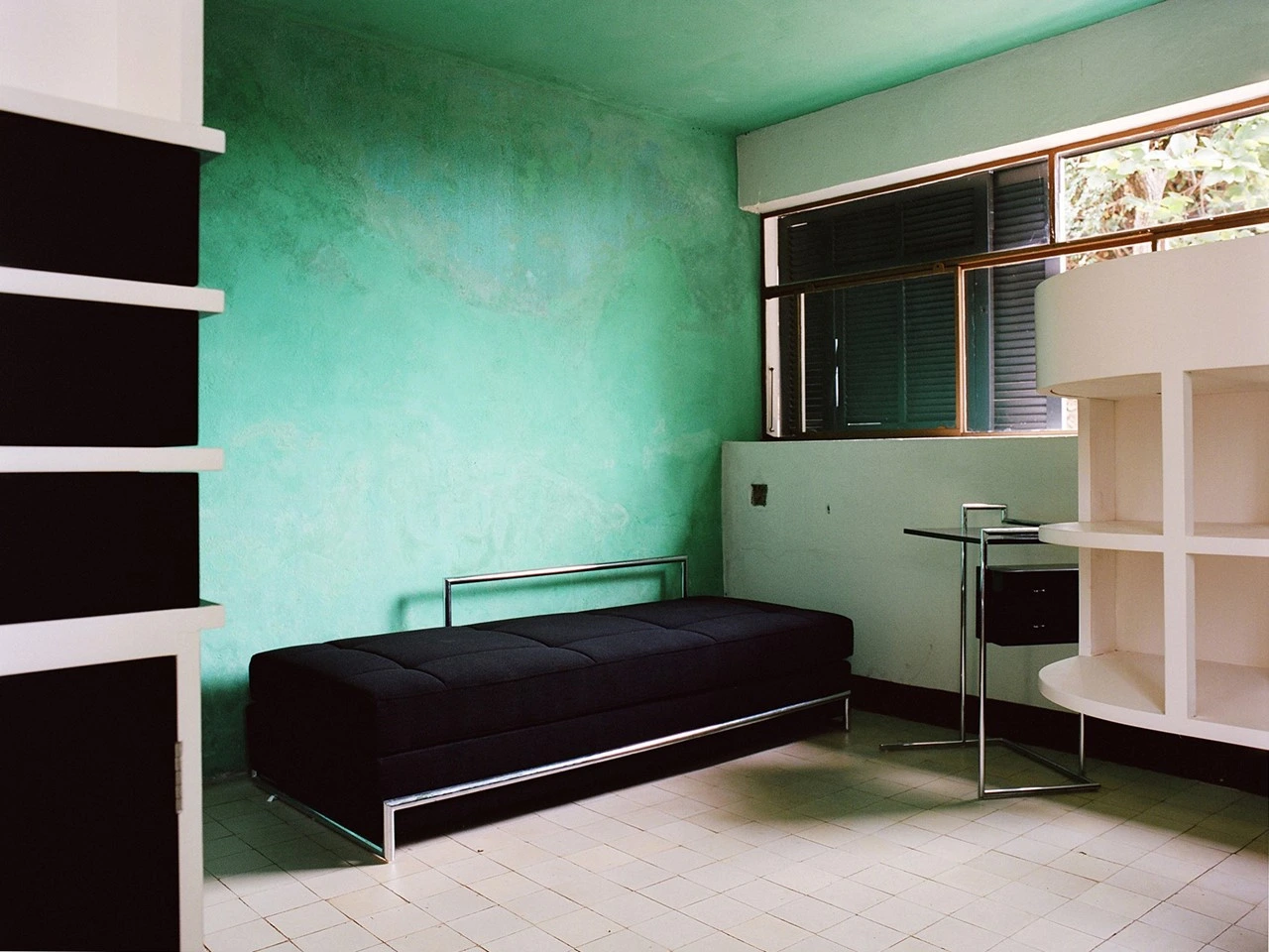 Inside E-1027. A room with green walls, white furniture and a black sofa