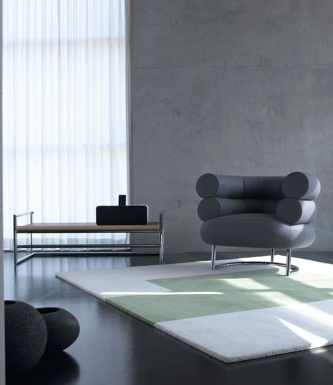 Eileen Gray’s Bibendum chair in interior. A black chair on a white square rug