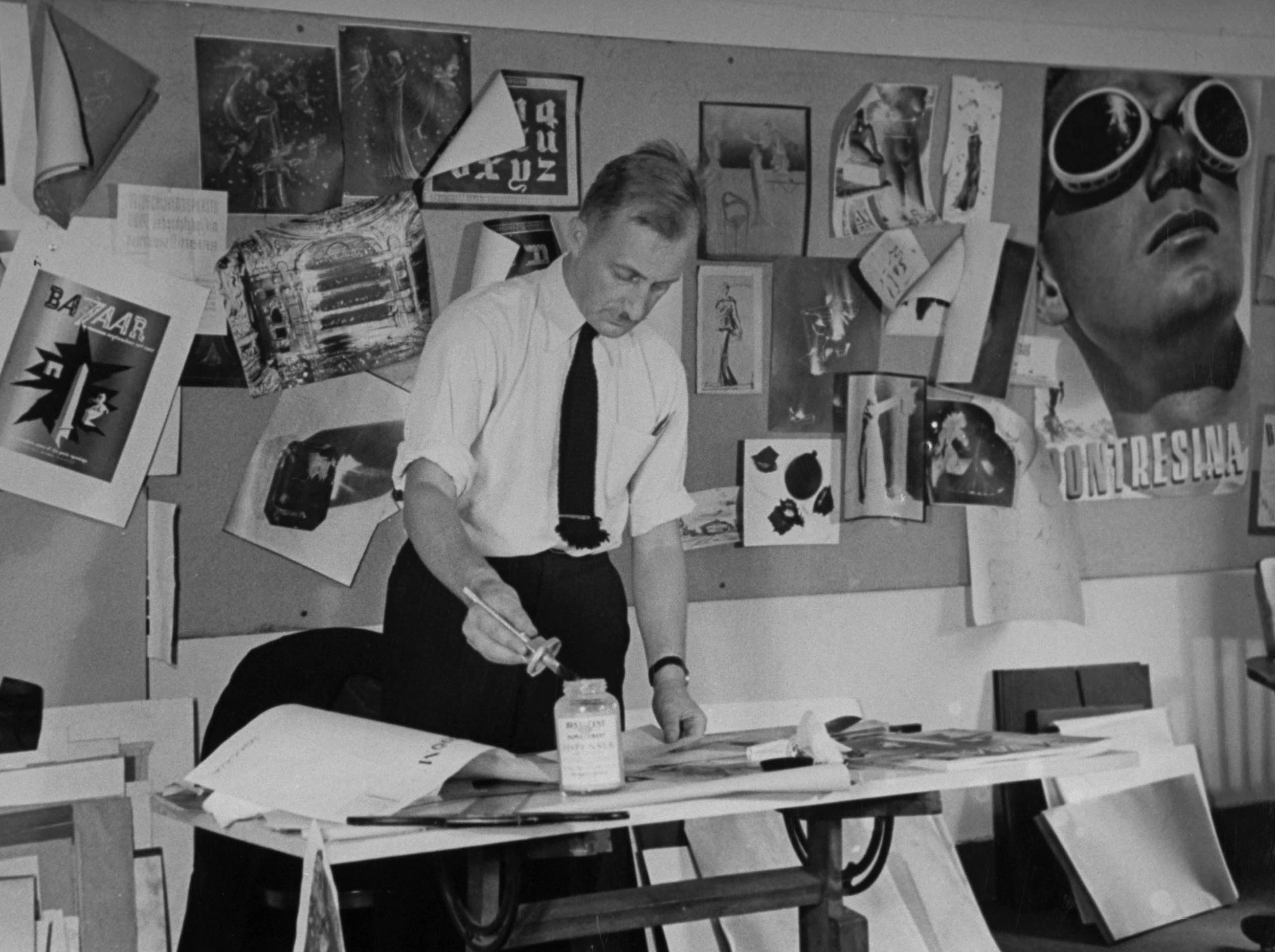 Alexey Brodovitch working on a fashion layout. Newspaper cuttings stuck to a wall