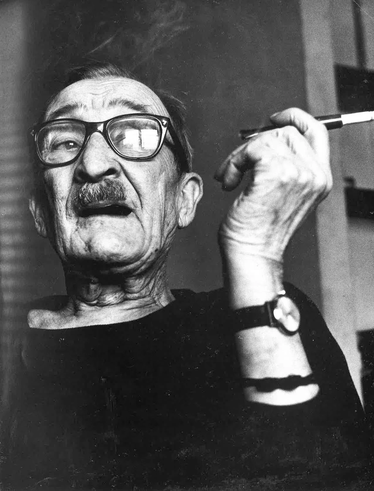 Alexey Brodovitch smoking, wearing glasses, with a moustache