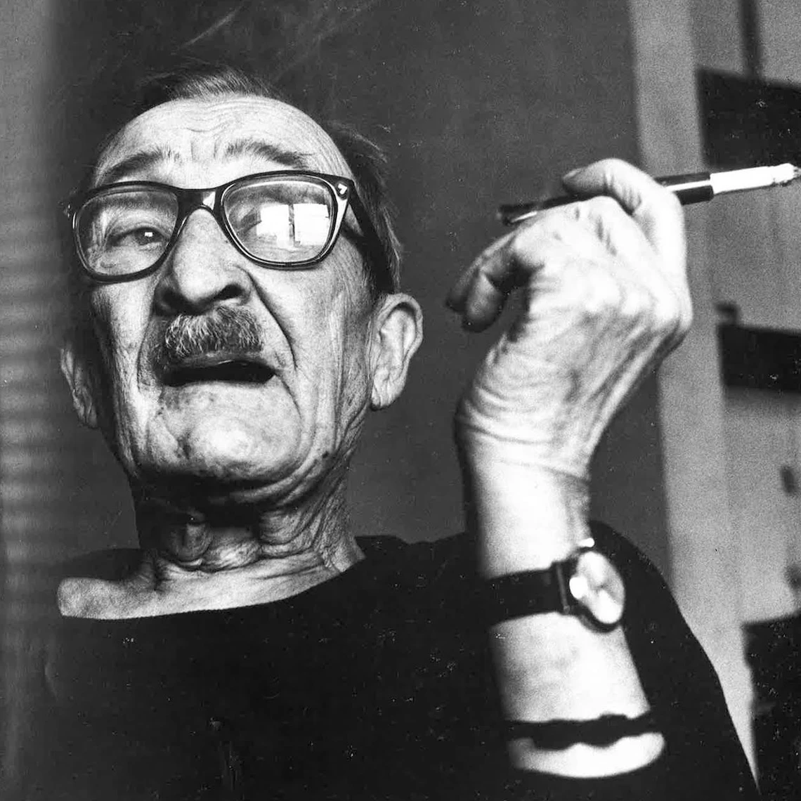 Alexey Brodovitch looking into camera, smoking a cigarette