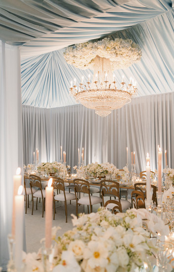 Indoor luxury wedding reception with candlelight and bountiful white florals at Beverly Hills wedding.