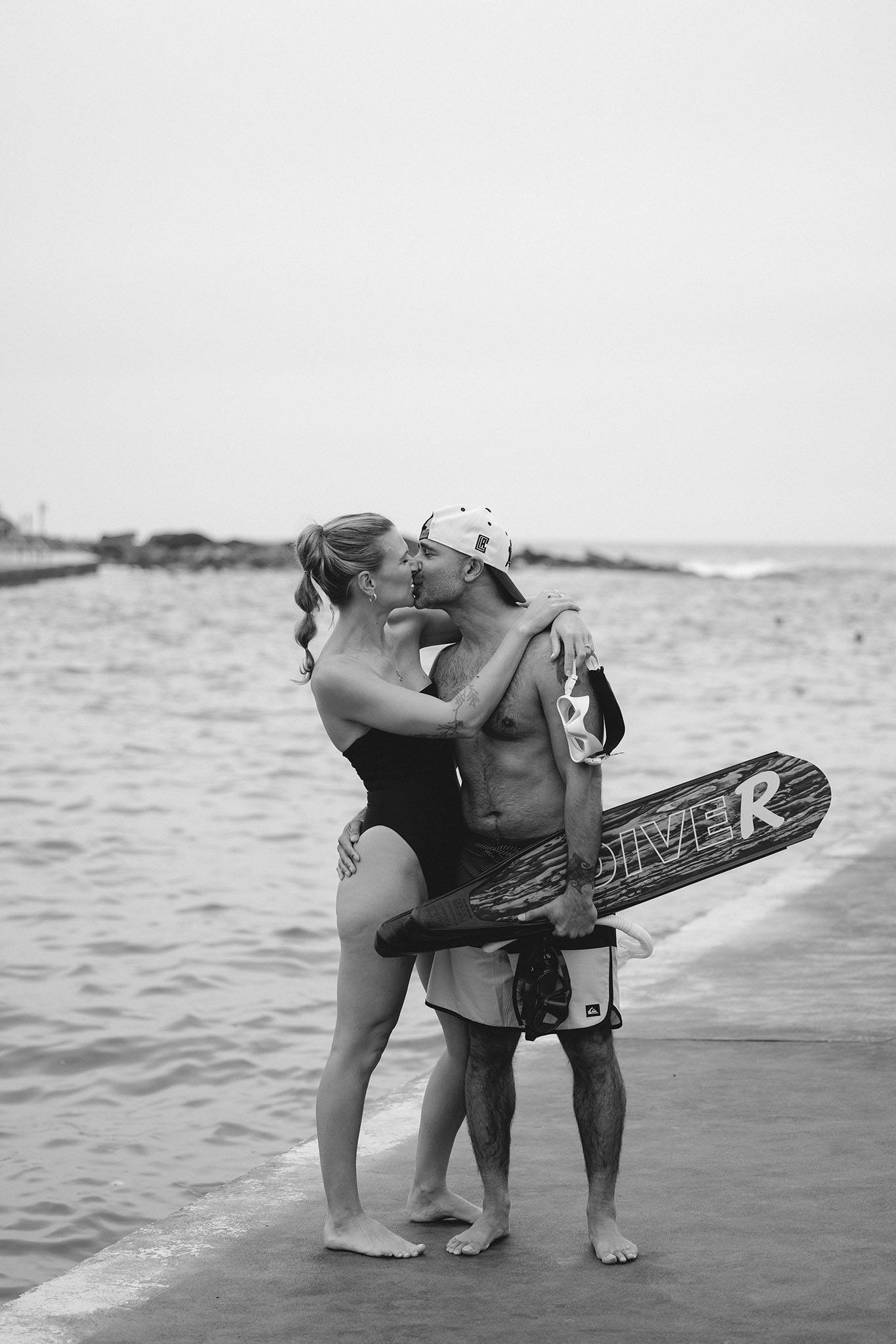 Bride and groom sharing a candid kiss after swimming at a beach in Malibu at sunset. Malibu Wedding Photographer.