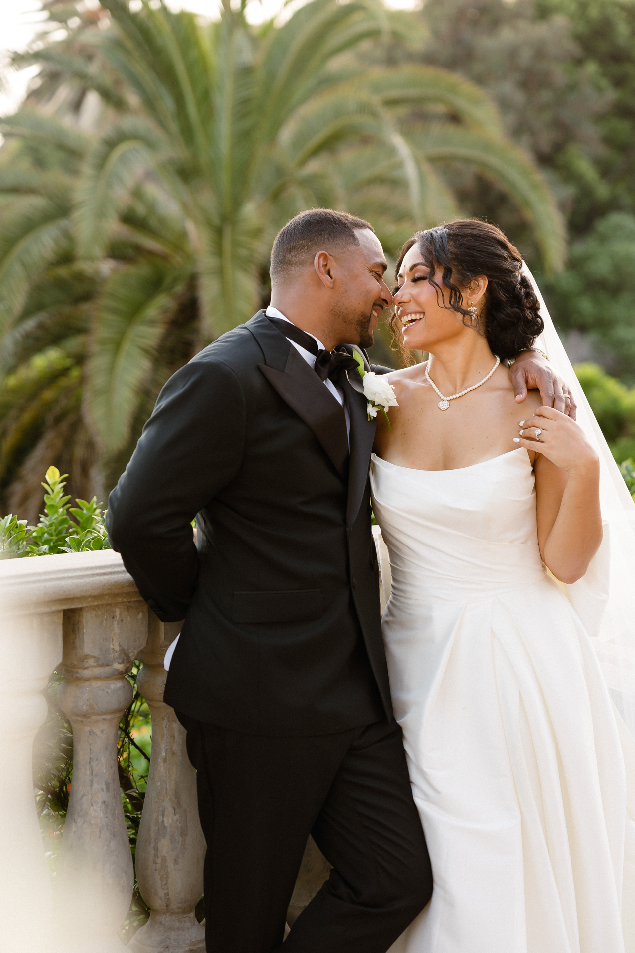 Bride and groom sharing an intimate kiss with an iconic Los Angeles sunset visible in the distance. Los Angeles wedding photography.