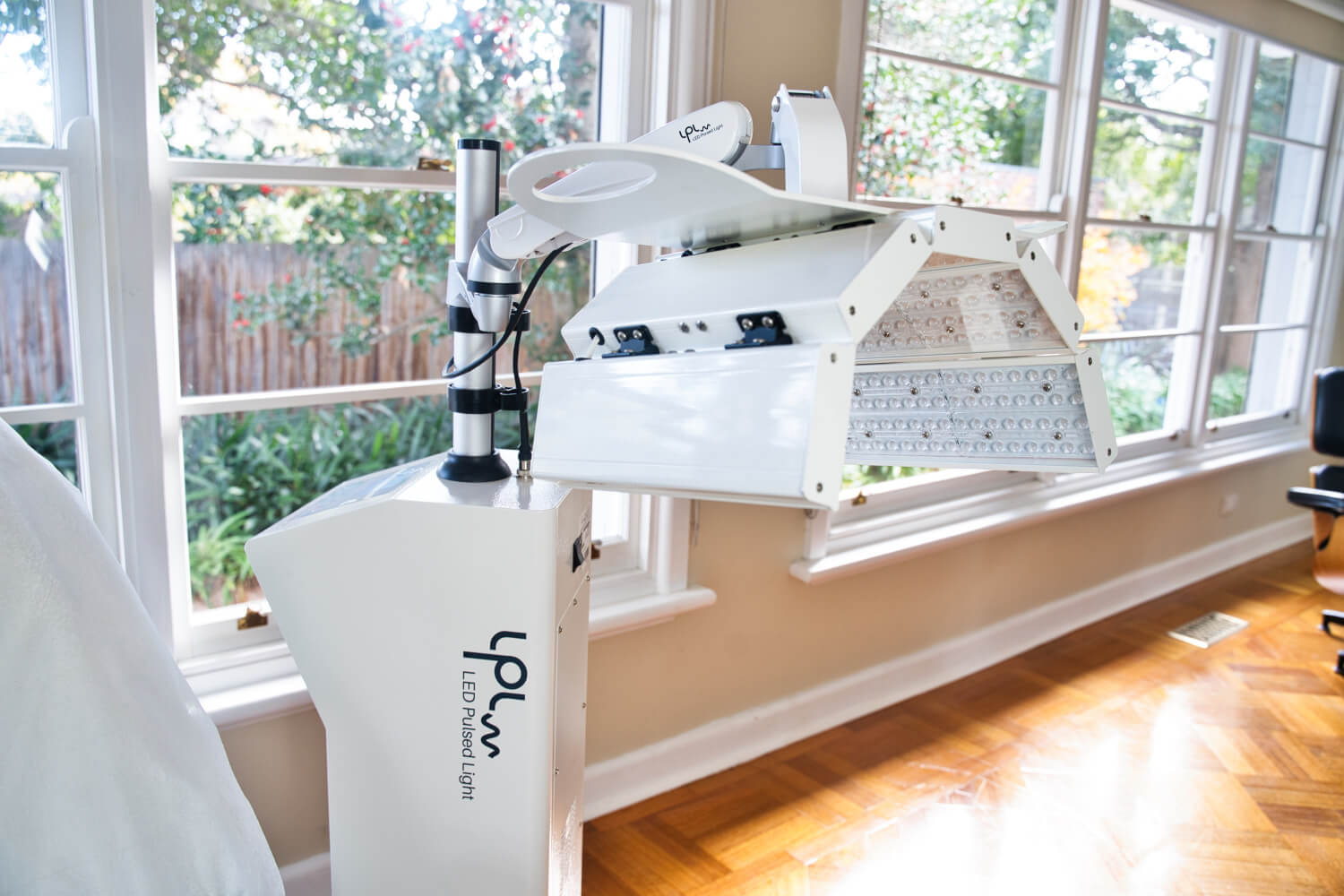 An LED Pulsed Light machine standing in a room with wooden floorboards and sash windows in the background