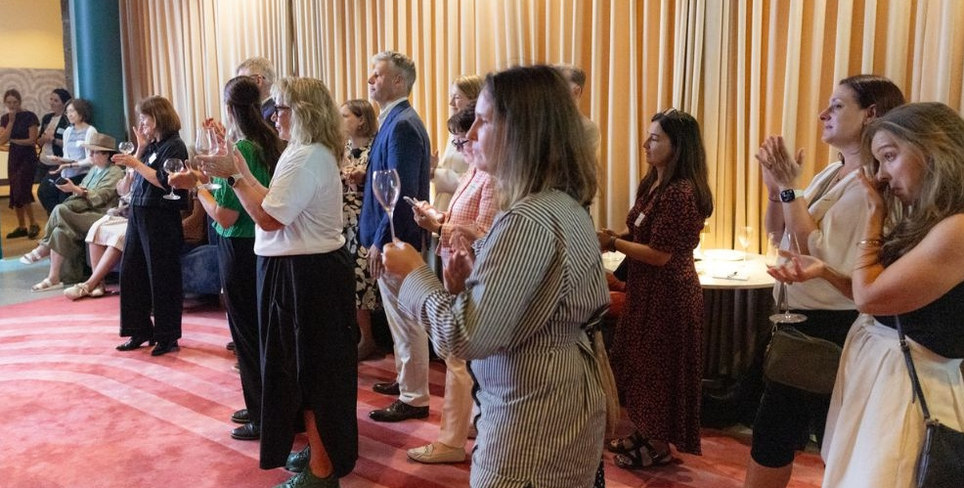 People attending the final Franklin Women farewell event, standing together and applauding in a venue.