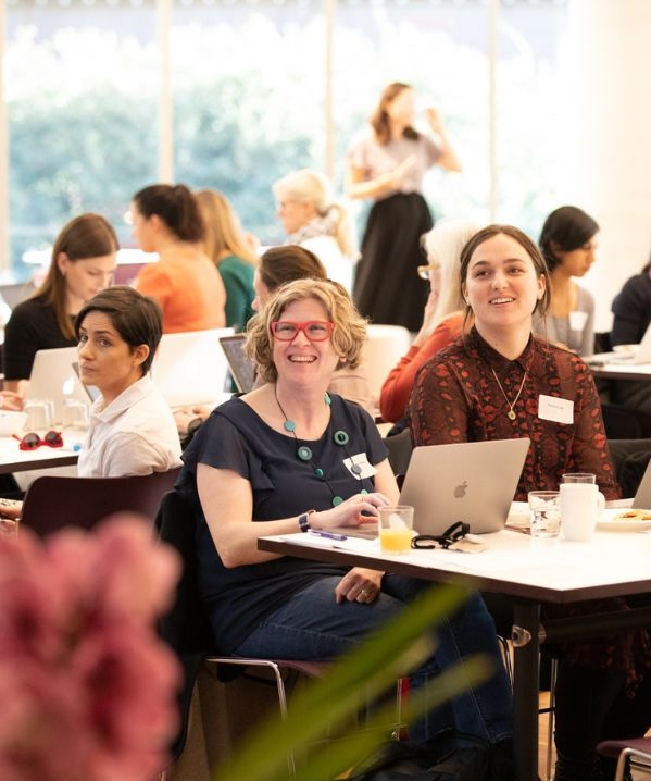Women seated at tables at a Franklin Women event, smiling and engaging in discussion during a workshop.