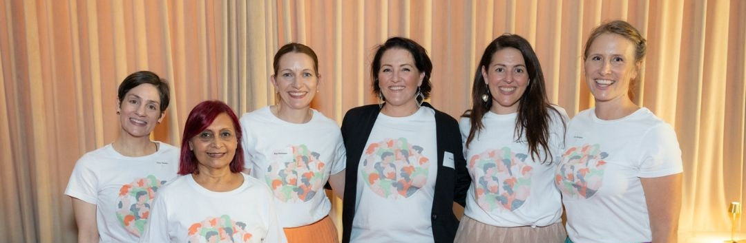 The Franklin Women team standing together and smiling at an event, wearing Franklin Women T-shirts.