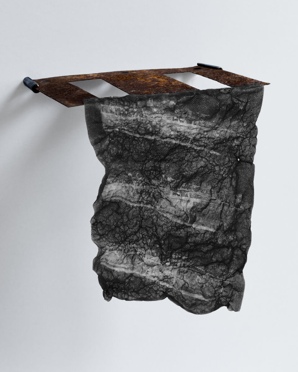 Water-soluble textile print molded by controlled exposure to water and suspended from a rusted textile machine part